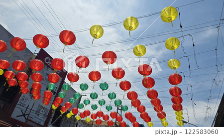 Vibrant red and yellow lanterns suspended across open balconies under a serene blue sky, representing festive celebrations of chinese new year and traditional cultural decor 122583060