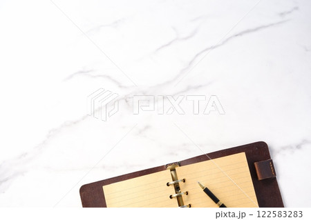 リング式のシステム手帳を開いてデスクワークをしているイメージ 122583283