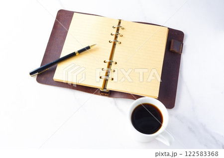 淹れたてのコーヒーを飲みながら、リング式のシステム手帳を開いてデスクワークをしているイメージ 122583368