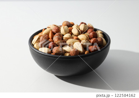 Assorted nuts in a black bowl on a white background 122584162