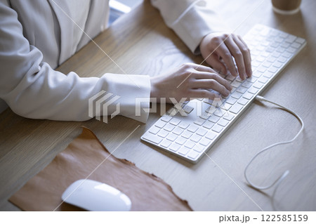 デスクトップパソコンで仕事をする女性の手元 122585159