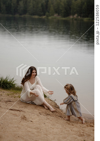 Mother and child on a lake shore in a serene moment. Mother and child on a lake shore in a serene moment. 122586059