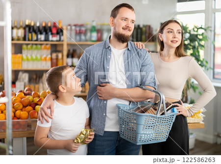 Family shopping - father, mother and son choose and buy products together in supermarket 122586263
