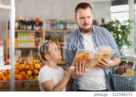 Young dad and tween son choosing packaged chicken in supermarket 122586271