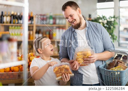 Young dad and tween son choosing packaged chicken in supermarket 122586284