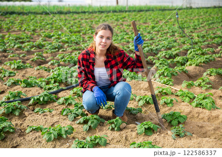 Portrait of young attractive female farmer with hoe 122586337