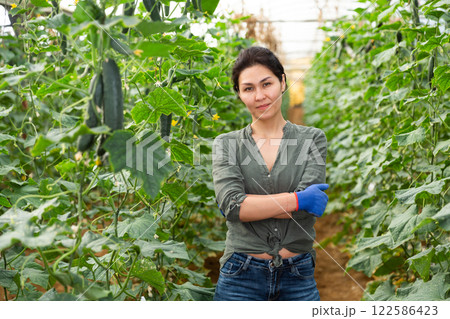 Woman standing in cucumber hothouse 122586423