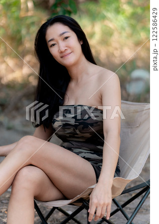 Portrait of sexy asian woman in a military print strapless dress, camping in the forest concept. 122586429