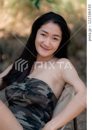 Portrait of sexy asian woman in a military print strapless dress, camping in the forest concept. 122586430
