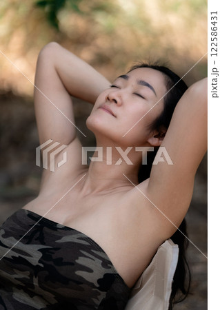 Portrait of sexy asian woman in a military print strapless dress, camping in the forest concept. 122586431