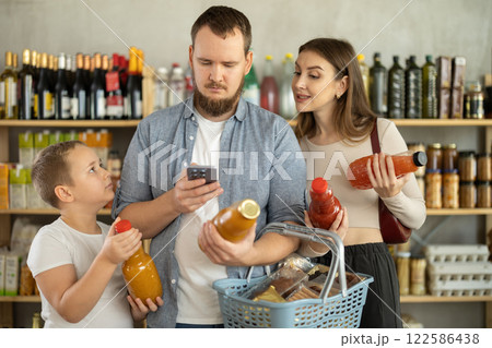 Family scanning barcodes on juice bottles while shopping in supermarket 122586438