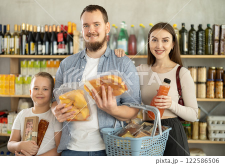 Young family with little son holding products in supermarket 122586506