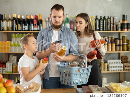 Young family with little son scanning QR on bottle of juice in supermarket 122586507