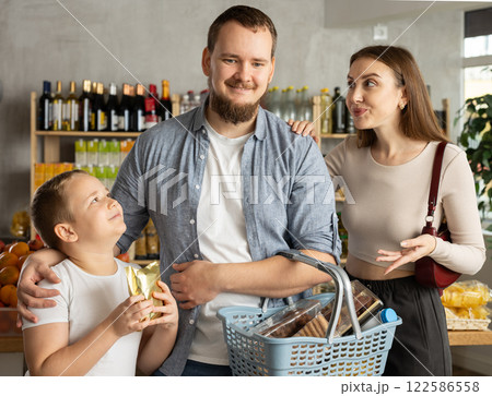 Couple of man and woman with boy choosing food in grocery Couple of man and woman with boy choosing food in grocery 122586558