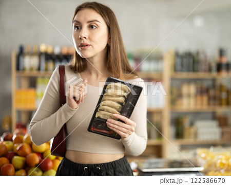 Young woman choosing jiaozi at grocery store 122586670