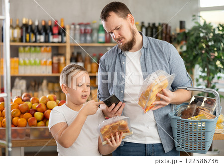 Tween boy with father scanning barcodes on packaged poultry parts in supermarket Tween boy with father scanning barcodes on packaged poultry parts in supermarket 122586736