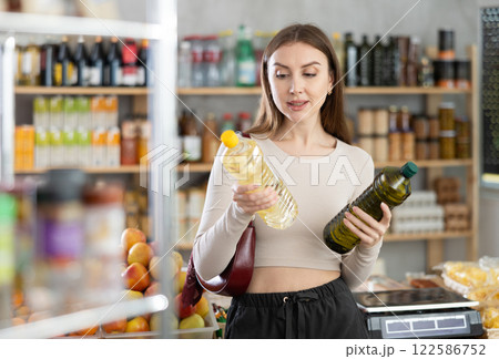 Young woman choosing olive and sunflower oil in grocery Young woman choosing olive and sunflower oil in grocery 122586752