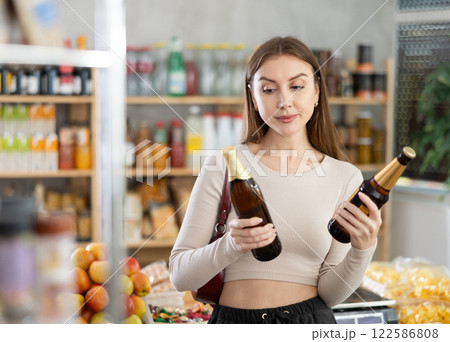 Young girl is choosing beer in grocery store Young girl is choosing beer in grocery store 122586808