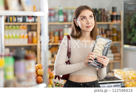 Woman chooses jiaozi are a type of Chinese dumpling to buy in the grocery department section of store Woman chooses jiaozi are a type of Chinese dumpling to buy in the grocery department section of store 122586818