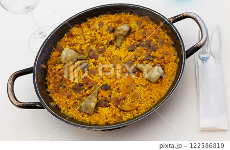 Delicious paella with meats and artichokes in traditional paellera Delicious paella with meats and artichokes in traditional paellera 122586819
