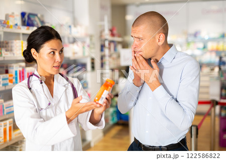 Female pharmacist helping man with toothache in drugstore Female pharmacist helping man with toothache in drugstore 122586822