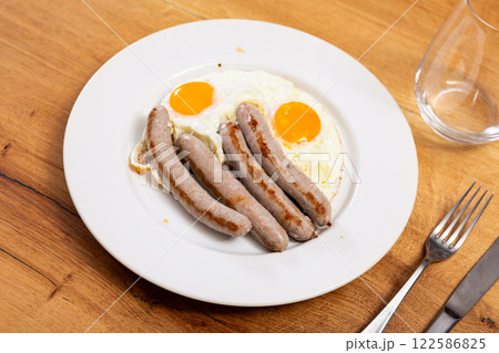 Fried eggs served with sausages on plate 122586825