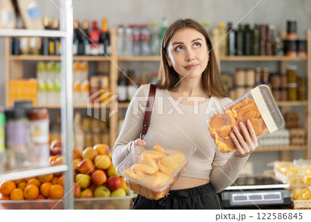 Female buyer carefully reads labels on packaging of semi-finished chicken products - she chooses best product in supermarket Female buyer carefully reads labels on packaging of semi-finished chicken products - she chooses best product in supermarket 122586845
