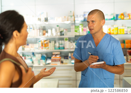 Buyer dictates the medicine to the pharmacist to write in notebook Buyer dictates the medicine to the pharmacist to write in notebook 122586850