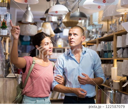 Couple choosing lamp at store of household goods Couple choosing lamp at store of household goods 122587079