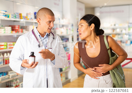 Oriental woman having stomach ache in chemist shop 122587081