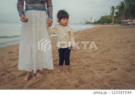 toddler baby girl walking with mother on sea beach in Pattaya, Thailand toddler baby girl walking with mother on sea beach in Pattaya, Thailand 122587244
