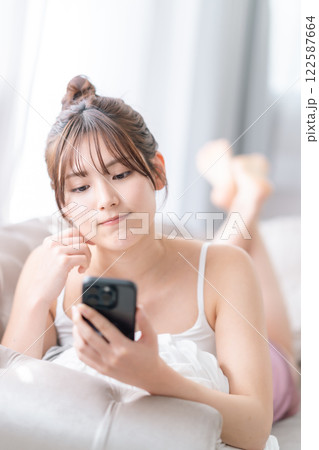 自宅でスマホを片手に返信を考える若い女性 自宅でスマホを片手に返信を考える若い女性 122587664