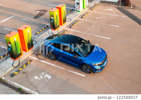 Blue electric vehicle is receiving power at a public charging point, top view  122588037