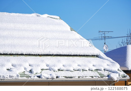 晴れて溶けかけている屋根に積もった雪 晴れて溶けかけている屋根に積もった雪 122588075