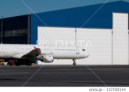 White passenger airplane near the aviation hangar White passenger airplane near the aviation hangar 122588144