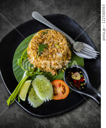 Fried rice in a black plate on a vintage cement dining table. 122588563