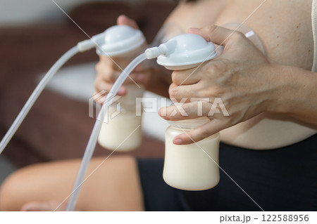 Mother pumps both breasts. Using an automatic pump machine. Motherhood and Child infant healthcare concept. Mother pumps both breasts. Using an automatic pump machine. Motherhood and Child infant healthcare concept. 122588956