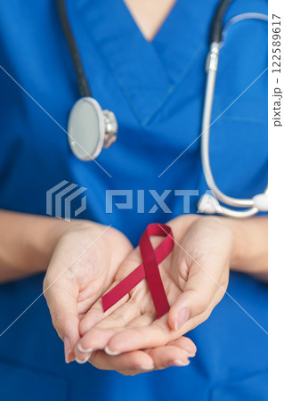 Doctor with Burgundy Red Ribbon for March multiple myeloma Cancer and December World Aids Day Awareness month. Healthcare and world cancer day concept Doctor with Burgundy Red Ribbon for March multiple myeloma Cancer and December World Aids Day Awareness month. Healthcare and world cancer day concept 122589617