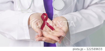 Doctor with Burgundy Red Ribbon for March multiple myeloma Cancer and December World Aids Day Awareness month. Healthcare and world cancer day concept 122589633