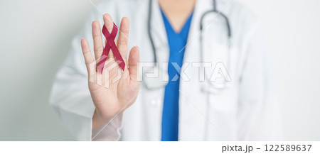 Doctor with Burgundy Red Ribbon for March multiple myeloma Cancer and December World Aids Day Awareness month. Healthcare and world cancer day concept 122589637