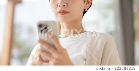 真剣な眼差しでスマホを見る女性 真剣な眼差しでスマホを見る女性 122589819