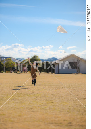 青空の下で凧揚げをする女の子 122590193