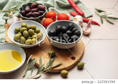 Black and green olives with olive oil, tomatoes, garlic and chili pepper on a wooden board Black and green olives with olive oil, tomatoes, garlic and chili pepper on a wooden board 122591394
