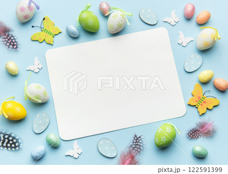 Easter decoration forming frame around blank card on blue background 122591399