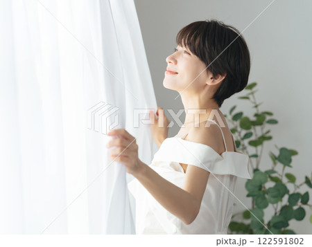 爽やかな笑顔でカーテンを開けるミドル女性 爽やかな笑顔でカーテンを開けるミドル女性 122591802