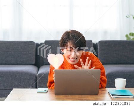 ノートパソコンでライブ配信を見ながら推し活するミドル女性 ノートパソコンでライブ配信を見ながら推し活するミドル女性 122591855