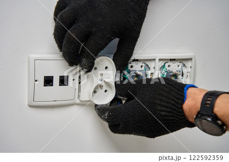 Electrician installing power socket on white wall 122592359