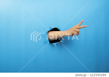 Human hand showing from ripped paper. Hand gestures of greeting or counting. Mockup or Copy space. Concept of sign or communication Human hand showing from ripped paper. Hand gestures of greeting or counting. Mockup or Copy space. Concept of sign or communication 122593284