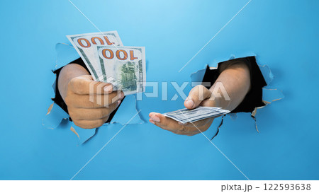 A human hand is holding dollar bills through ripped paper. Mockup or Copy space. Concept of economy and finance 122593638