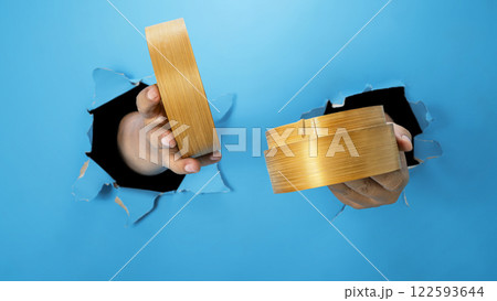A human hand is holding a bamboo steamer through ripped paper. Hand gestures to serve food. Mockup or Copy space 122593644